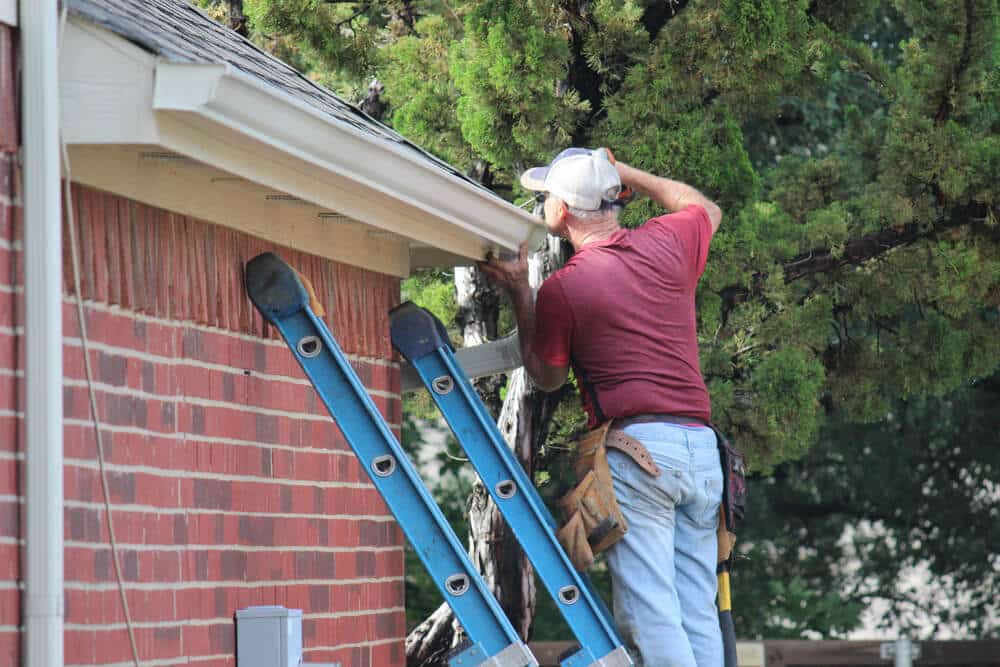 Werknemer die nieuwe dakgoten aan huis bevestigt | www.phillyaptrentals.com