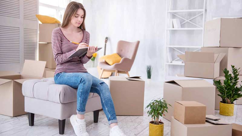 Femme avec liste de contrôle et cartons de déménagement dans l'appartement | www.phillyaptrentals.com