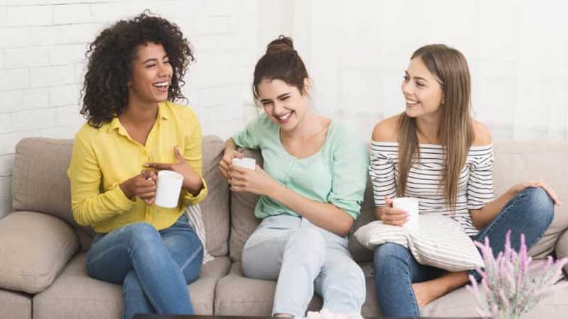Three women sitting on couch inside an apartment