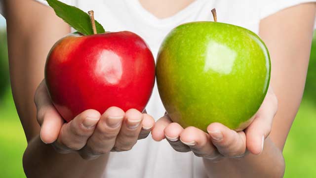 Manos sosteniendo una manzana roja y verde