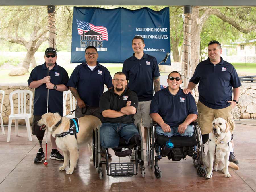 Foto de veteranos heridos posando delante del Homes for Our Troops bandera