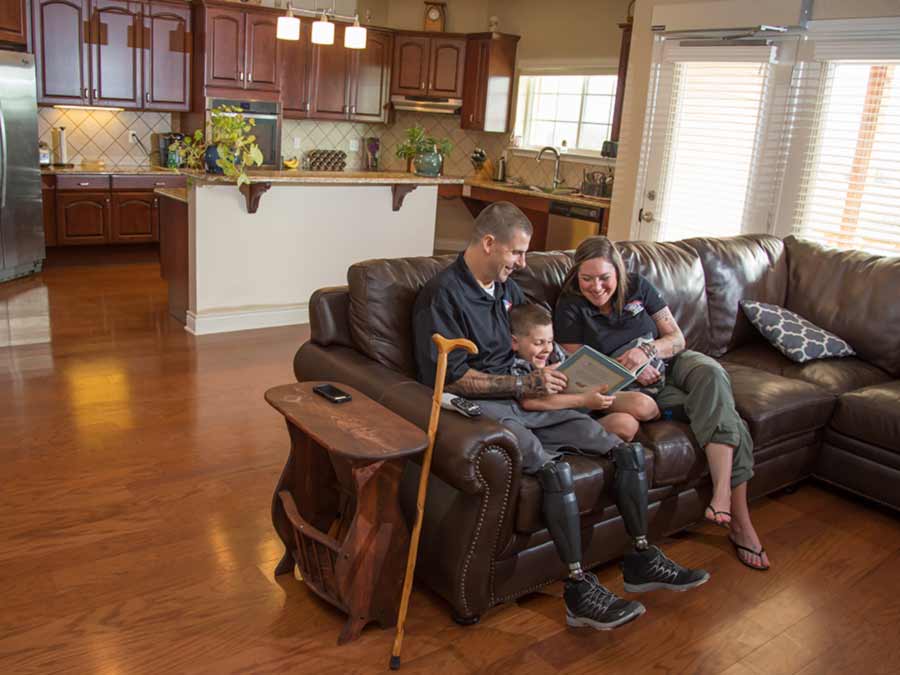 Veteran and his wife on the couch reading to their son