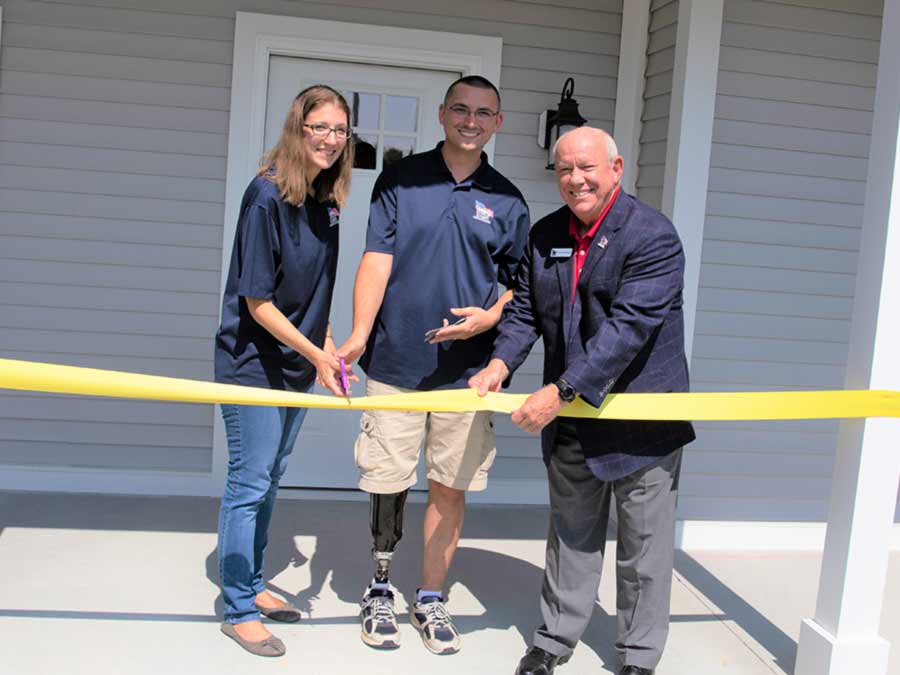 Young veteran man with his wife cutting the ribbon to open his new home