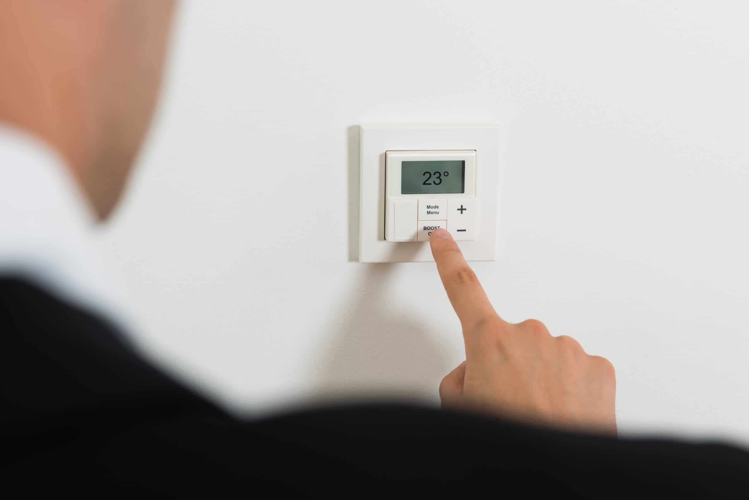 Großer Mann, der den Thermostat wechselt