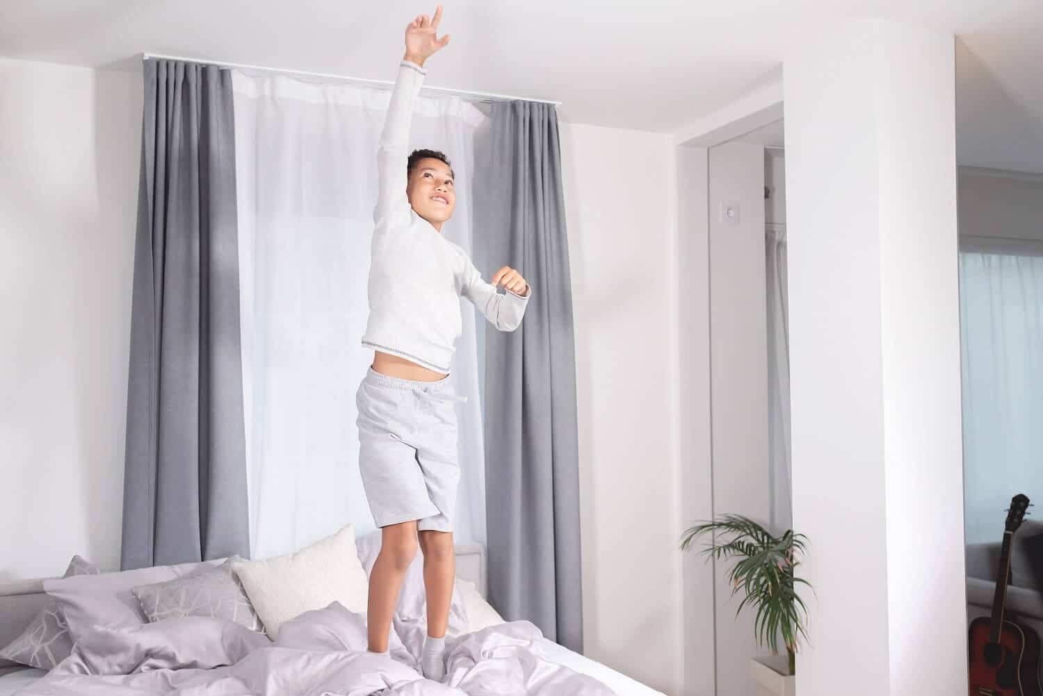 What is the Average Ceiling Height in an Apartment | boy on bed reaching to touch ceiling | www.phillyaptrentals.com
