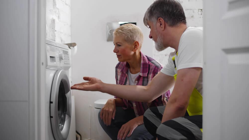 What Does Apartment Maintenance Include | Woman and Man Reviewing Broken Washer | www.phillyaptrentals.com